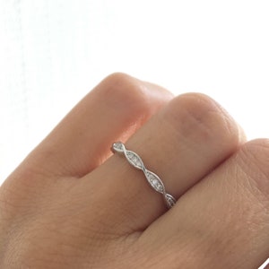 May include: A silver band ring with a twisted design and small clear stones set in the band.