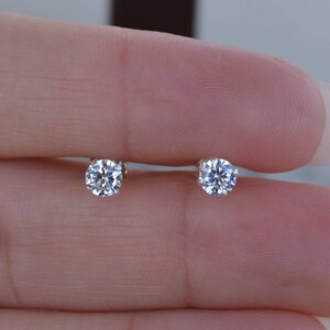 May include: A pair of small, round, clear diamond stud earrings.