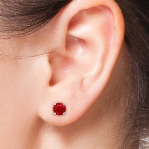 Może przedstawiać: Para czerwonych kamieni szlachetnych kolczyków w srebrnym oprawie.