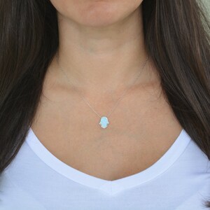 Peut inclure: Un collier en cha&icirc;ne argent avec un pendentif main de Hamsa bleu clair.
