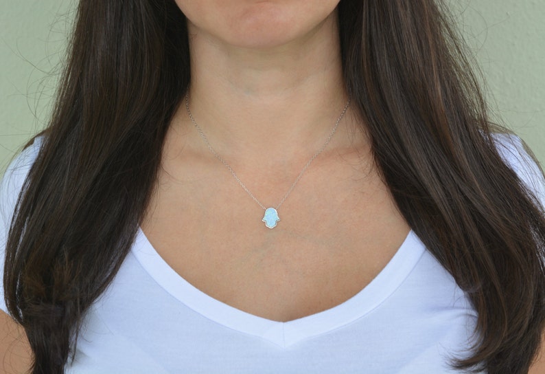 Peut inclure: Un collier en cha&icirc;ne argent avec un pendentif main de Hamsa bleu clair.