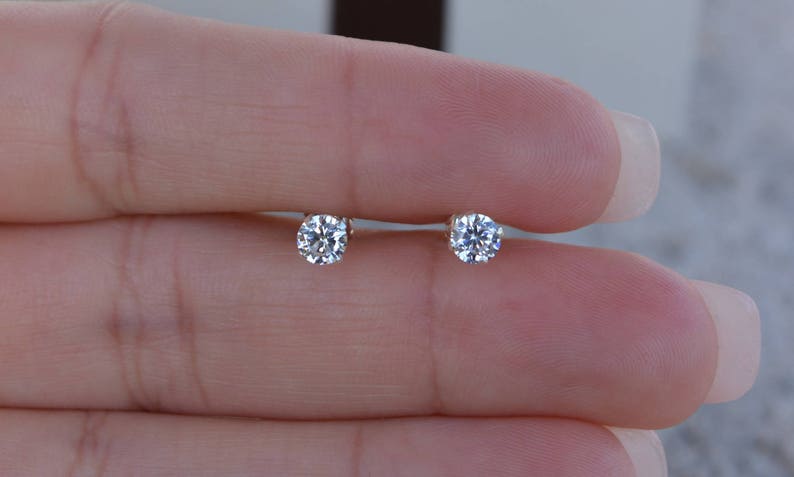 May include: A pair of small, round, clear diamond stud earrings.