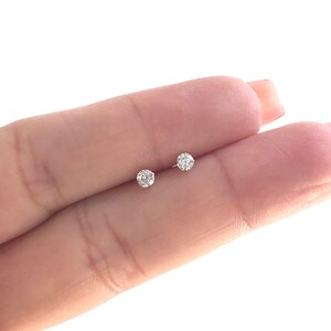 May include: A pair of small, round, clear diamond stud earrings.