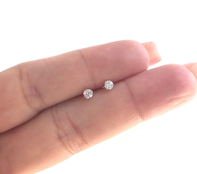 May include: A pair of small, round, clear diamond stud earrings.