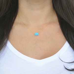 May include: A delicate gold chain necklace with a small turquoise elephant pendant.