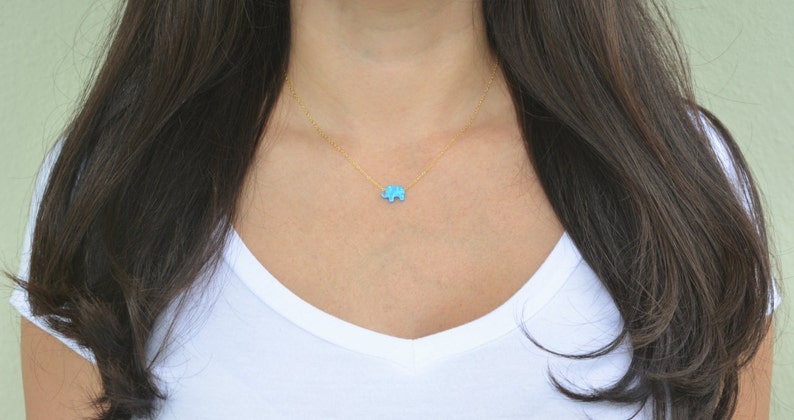 May include: A delicate gold chain necklace with a small turquoise elephant pendant.