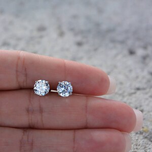 May include: A pair of silver stud earrings with clear round cubic zirconia stones.