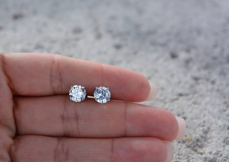 May include: A pair of silver stud earrings with clear round cubic zirconia stones.