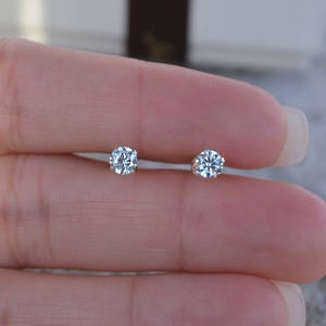 May include: A pair of small, round, clear diamond stud earrings.