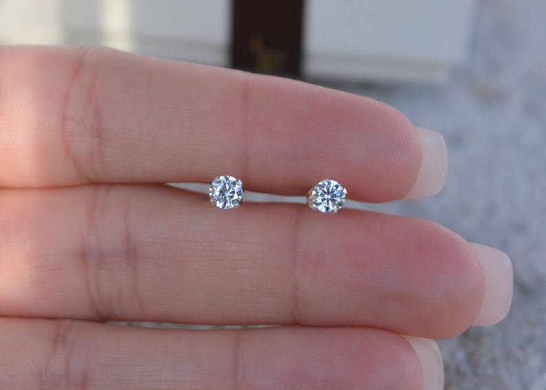 May include: A pair of small, round, clear diamond stud earrings.