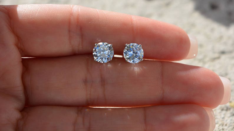May include: A pair of round, clear, sparkling diamond stud earrings.