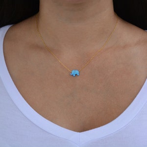 May include: A gold chain necklace with a small blue opal elephant pendant.