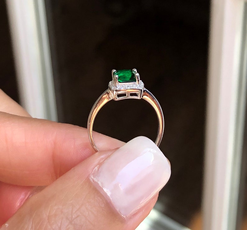 Puede incluir: Un anillo de plata con una esmeralda verde rodeada por un halo de diamantes m&aacute;s peque&ntilde;os.