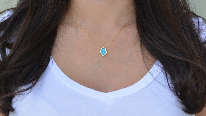 Peut inclure: Un collier en cha&icirc;ne dor&eacute;e avec un pendentif en forme de main de Hamsa turquoise.