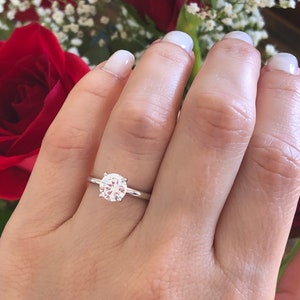 May include: A silver solitaire engagement ring with a round, clear diamond set in a simple band.