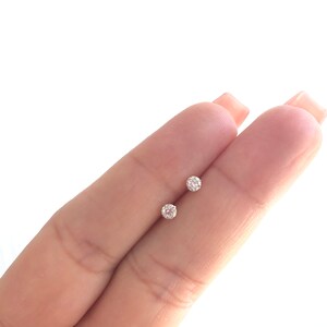 May include: A pair of small, round, clear diamond stud earrings.