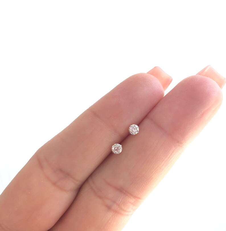 May include: A pair of small, round, clear diamond stud earrings.