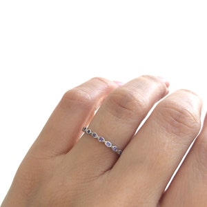 May include: A silver band ring with a row of small purple gemstones.