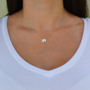 May include: A silver chain necklace with a small, white opal elephant pendant.