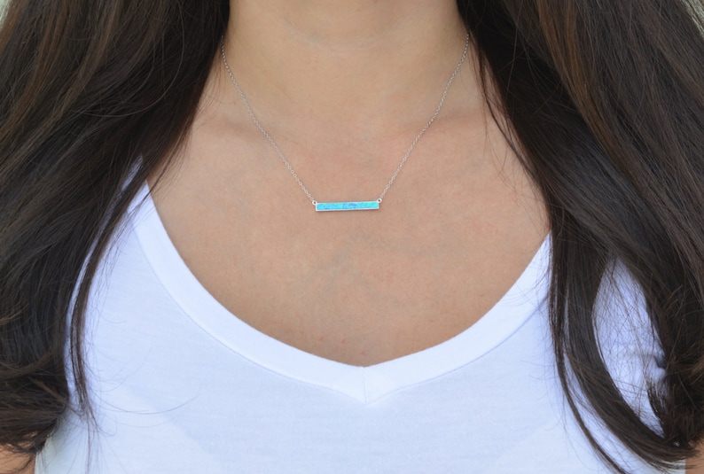 May include: A silver chain necklace with a turquoise bar pendant.