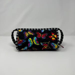 May include: Black quilted makeup bag with a zipper closure and a black and white checkered trim. The bag is decorated with a colorful butterfly print.