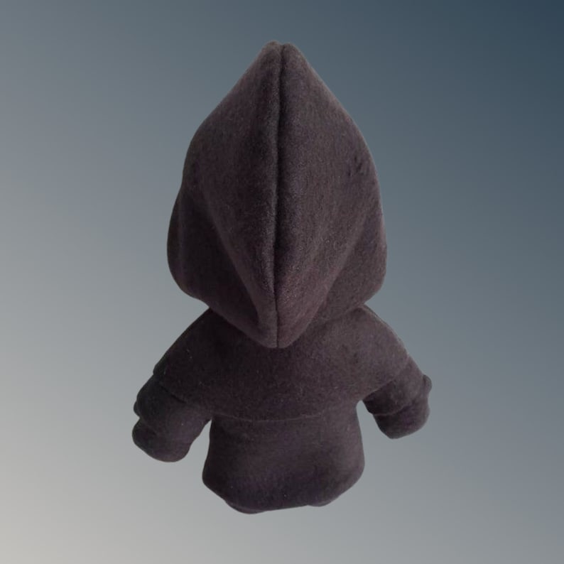 May include: A dark grey hooded cloak, seen from the back, featuring a pointed hood and small sleeves. The cloak is made of a soft, textured fabric. The background is a grey and blue gradient.