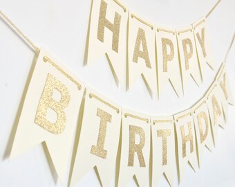 May include: A white banner with gold glitter letters spelling "Happy Birthday".