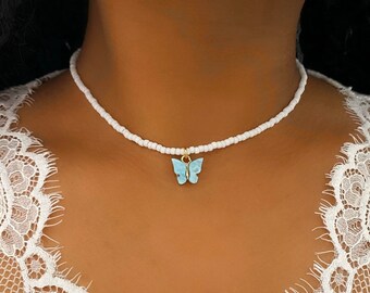 May include: A white beaded choker necklace with a light blue butterfly charm.