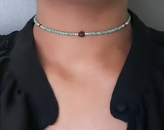 May include: A delicate choker necklace with small turquoise and silver beads and a brown gemstone accent.
