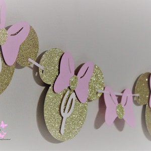 May include: Gold glitter Minnie Mouse ears with pink bows and white letters spelling "D-I-S-N-E-Y" for a birthday party decoration.