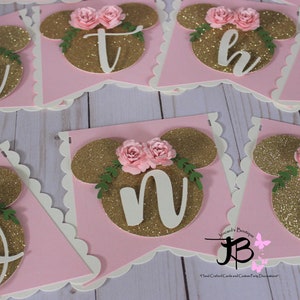 Puede incluir: Bandera de brillo rosa y dorado con letras blancas que deletrean la palabra "one". Cada letra est&aacute; decorada con una flor rosa y hojas verdes.