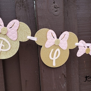 May include: Gold and pink Minnie Mouse themed banner with the letters "D" and "4" on it.