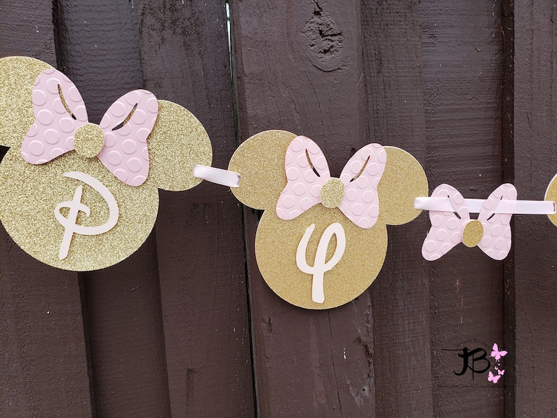 May include: Gold and pink Minnie Mouse themed banner with the letters "D" and "4" on it.