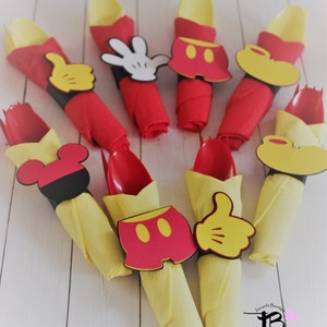 May include: A collection of party decorations featuring red napkins with yellow spoons, adorned with Mickey Mouse-themed cutouts. The decorations include Mickey's gloves, shorts, and head shapes, perfect for a themed party.