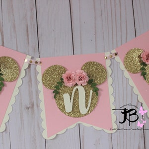 Puede incluir: Bandera de brillo rosa y dorado con las letras "ONE" en brillo dorado, cada letra est&aacute; decorada con una flor rosa y hojas verdes. La bandera es perfecta para una fiesta de primer cumplea&ntilde;os.