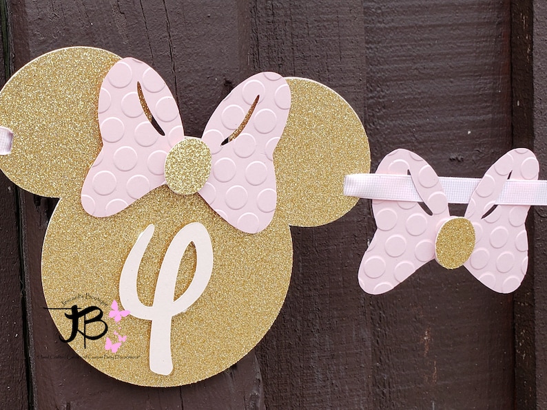 May include: Gold glitter Minnie Mouse ears with a pink bow and white number "4" on the front. The ears are attached to a pink bow with gold glitter accents.