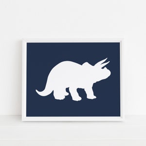 May include: White silhouette of a triceratops dinosaur on a dark blue background. The image is framed in a white frame.