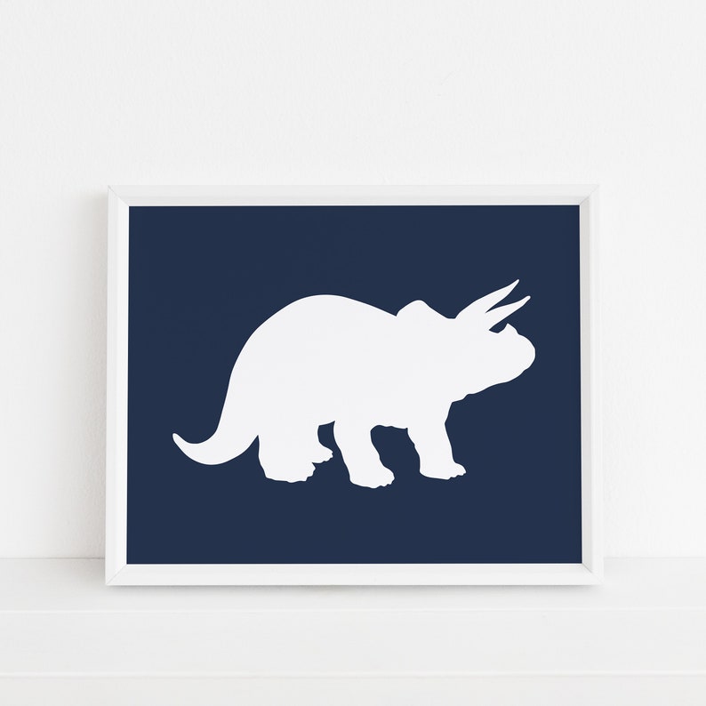 May include: White silhouette of a triceratops dinosaur on a dark blue background. The image is framed in a white frame.