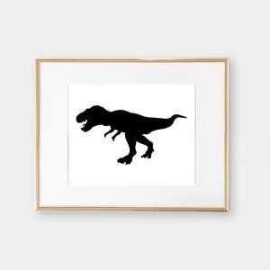 May include: A black silhouette of a Tyrannosaurus Rex dinosaur in a gold frame.