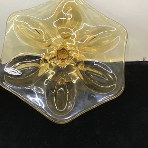 May include: A clear amber glass bowl with a five-pointed star shape and a textured surface. The bowl has a small hole in the center of the bottom. The bowl is made by Smith Glass.