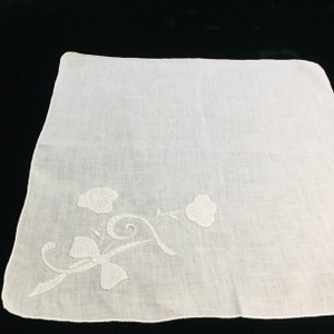 May include: White cotton handkerchief with delicate white embroidered floral design.
