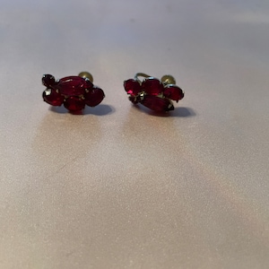 Könnte beinhalten: Ein Paar vintage Ohrclips mit einem Cluster aus roten Strasssteinen.