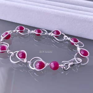 May include: A silver bracelet featuring pink gemstone beads. The bracelet is crafted with wire wrapped around each bead, resulting in a delicate and intricate design.