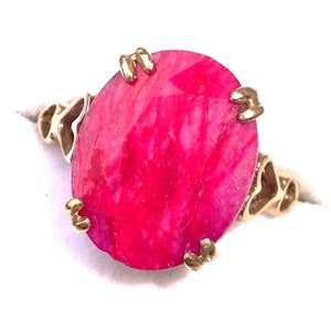 May include: A gold ring featuring a large, round, pink gemstone. The gemstone has a swirling pattern.