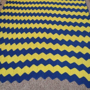 May include: A crocheted blanket with a chevron pattern in yellow and blue.