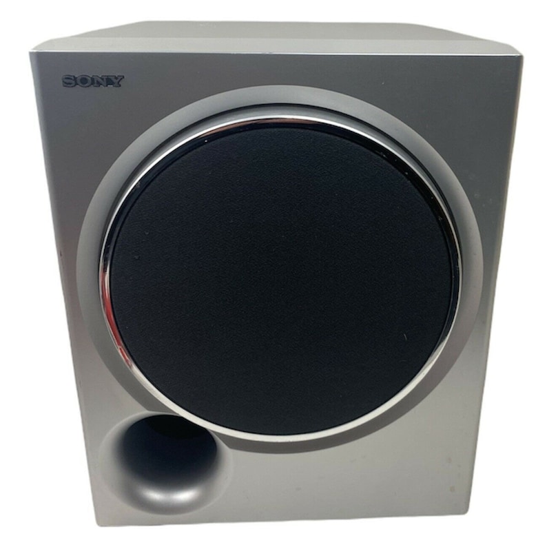 Pu&ograve; includere: Un subwoofer Sony argentato con un grande cono di altoparlante nero e una porta pi&ugrave; piccola sul davanti.