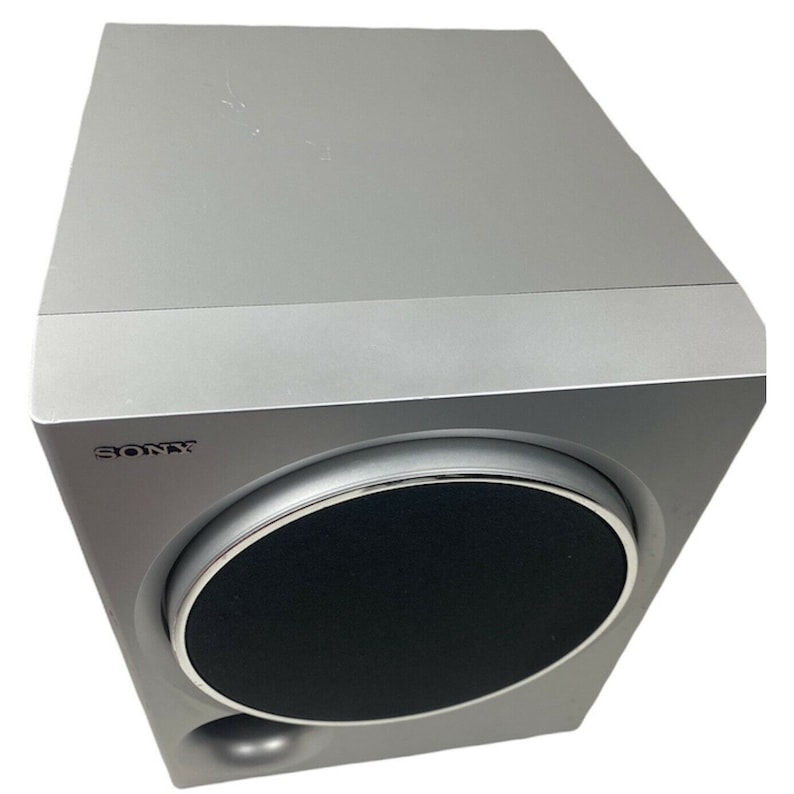 Pu&ograve; includere: Un subwoofer Sony argentato con una griglia dell'altoparlante nera. Il subwoofer ha un fronte arrotondato e una forma rettangolare.