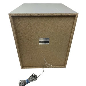 Pu&ograve; includere: Un subwoofer Sony bianco con una griglia dell'altoparlante marrone e un'etichetta sul retro che recita "Sony 5.1ch Home Theater System". Il subwoofer ha un filo grigio.