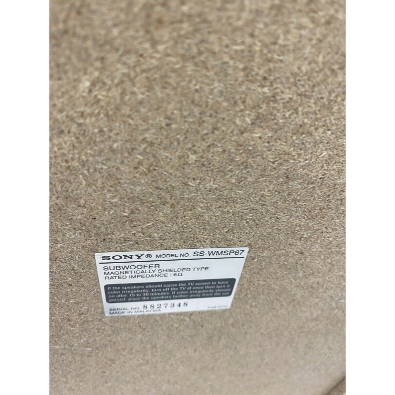 Pu&ograve; includere: Un'etichetta bianca con testo nero su un altoparlante marrone. L'etichetta recita "SONY MODEL NO. SS-WMSP67 SUBWOOFER MAGNETICALLY SHIELDED TYPE RATED IMPEDANCE: 6&Omega; Se gli altoparlanti dovessero causare irregolarit&agrave; di colore sullo schermo del televisore, spegnere immediatamente il televisore e quindi spegnere l'audio dopo 15-30 minuti. Se l'irregolarit&agrave; di colore persiste, posizionare gli altoparlanti pi&ugrave; lontano. SERIAL NO. 8827348 MADE IN MALAYSIA"