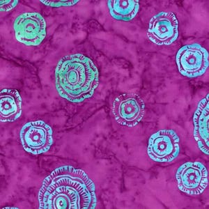 May include: A fabric with a vibrant purple background, featuring a repeating pattern of stylized floral designs in shades of teal and green. The flowers have a layered, circular design, creating a textured appearance. The fabric has a marbled effect.